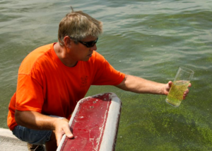 A man holding a cup full of algae water